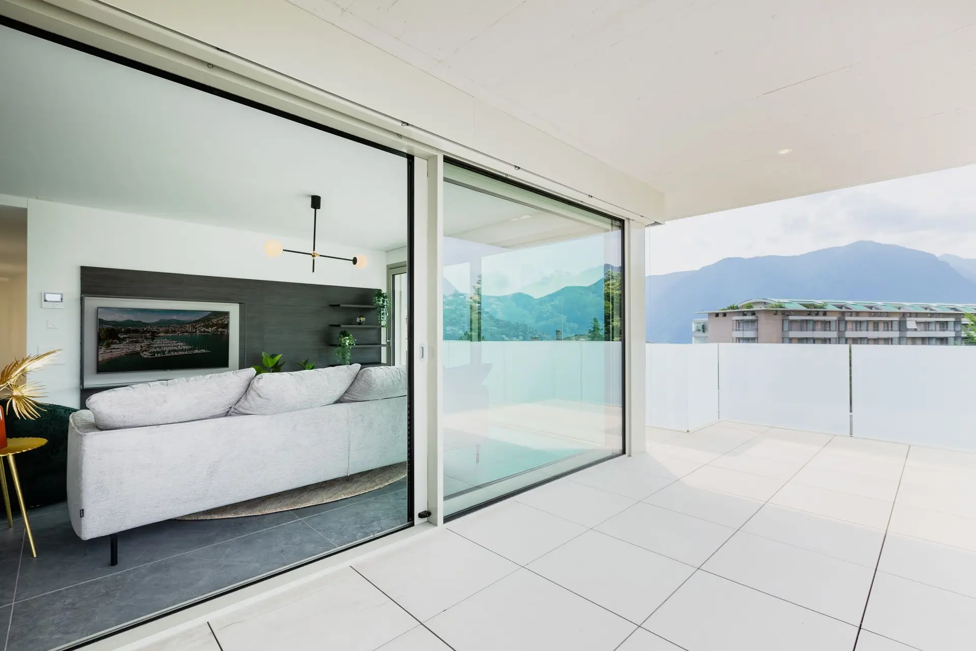 Living room with a wide sliding glass wall open to a terrace and hills
