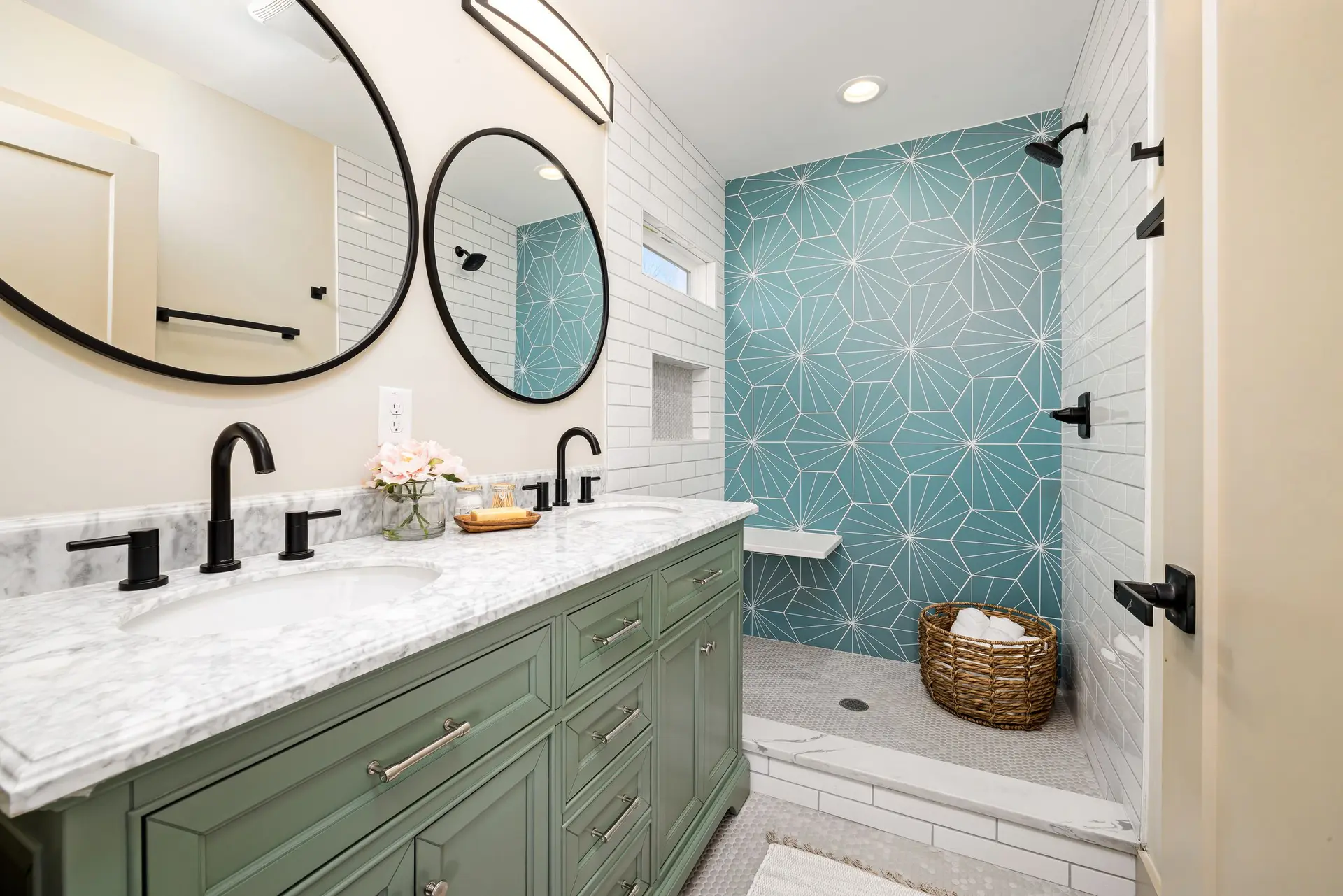 Bathroom with a green vanity, round mirrors and a teal tiled shower