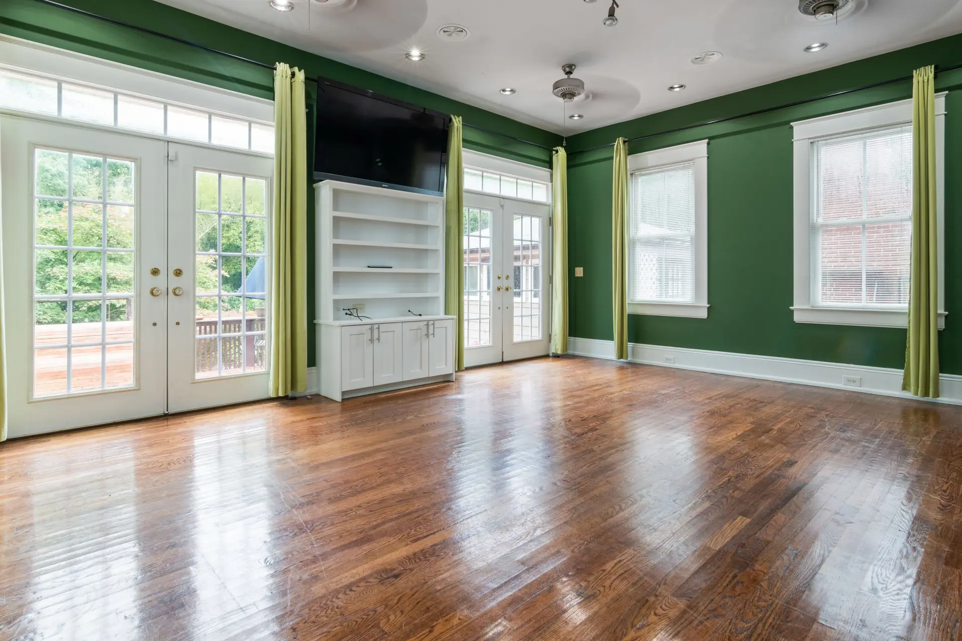 Empty room with wood floors and two pairs of French doors to the yard