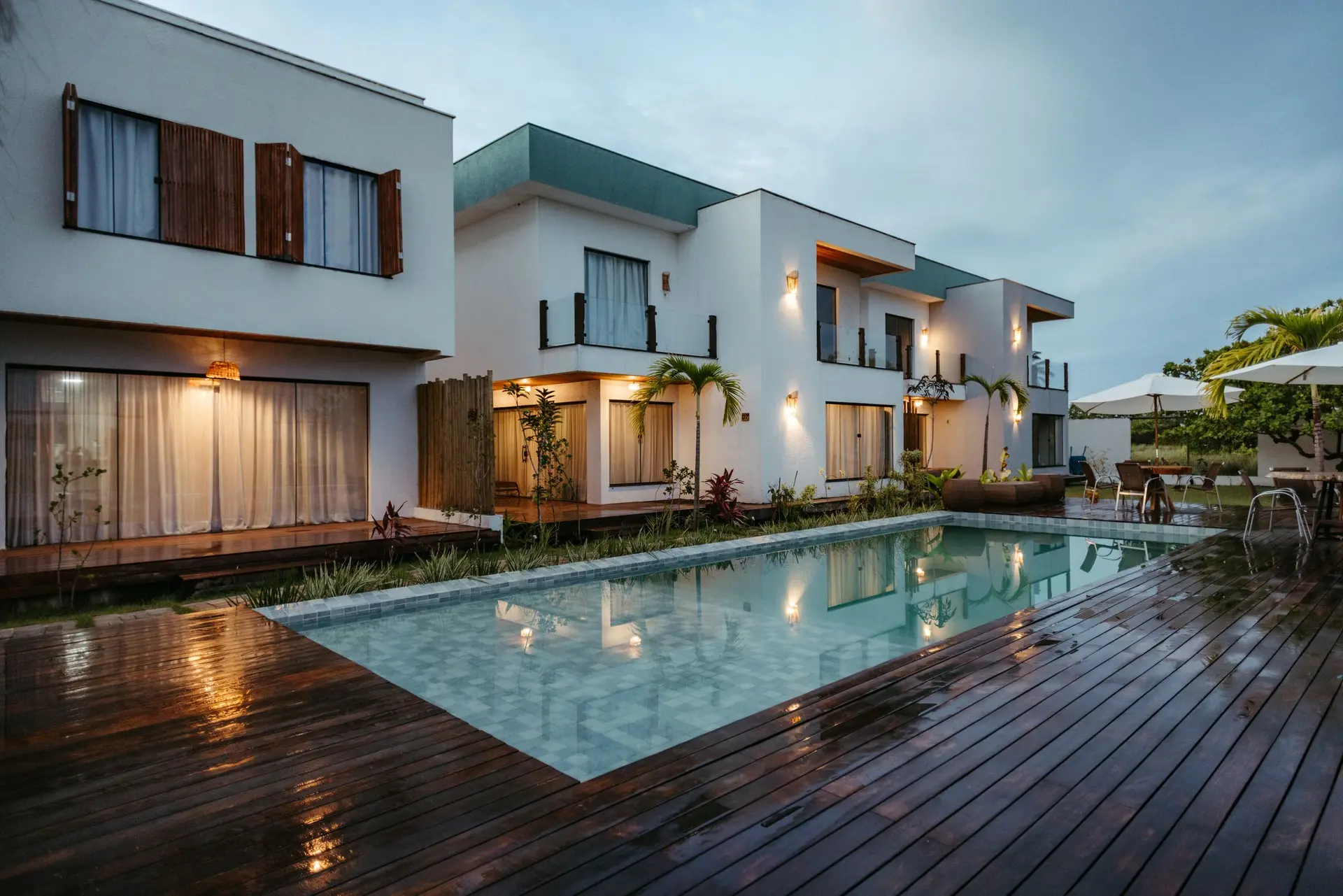 Wood pool deck between modern houses at dusk