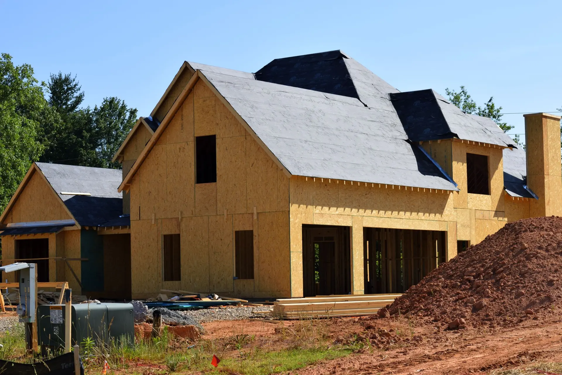 Partly built wood frame house with sheathed walls and a dark roof