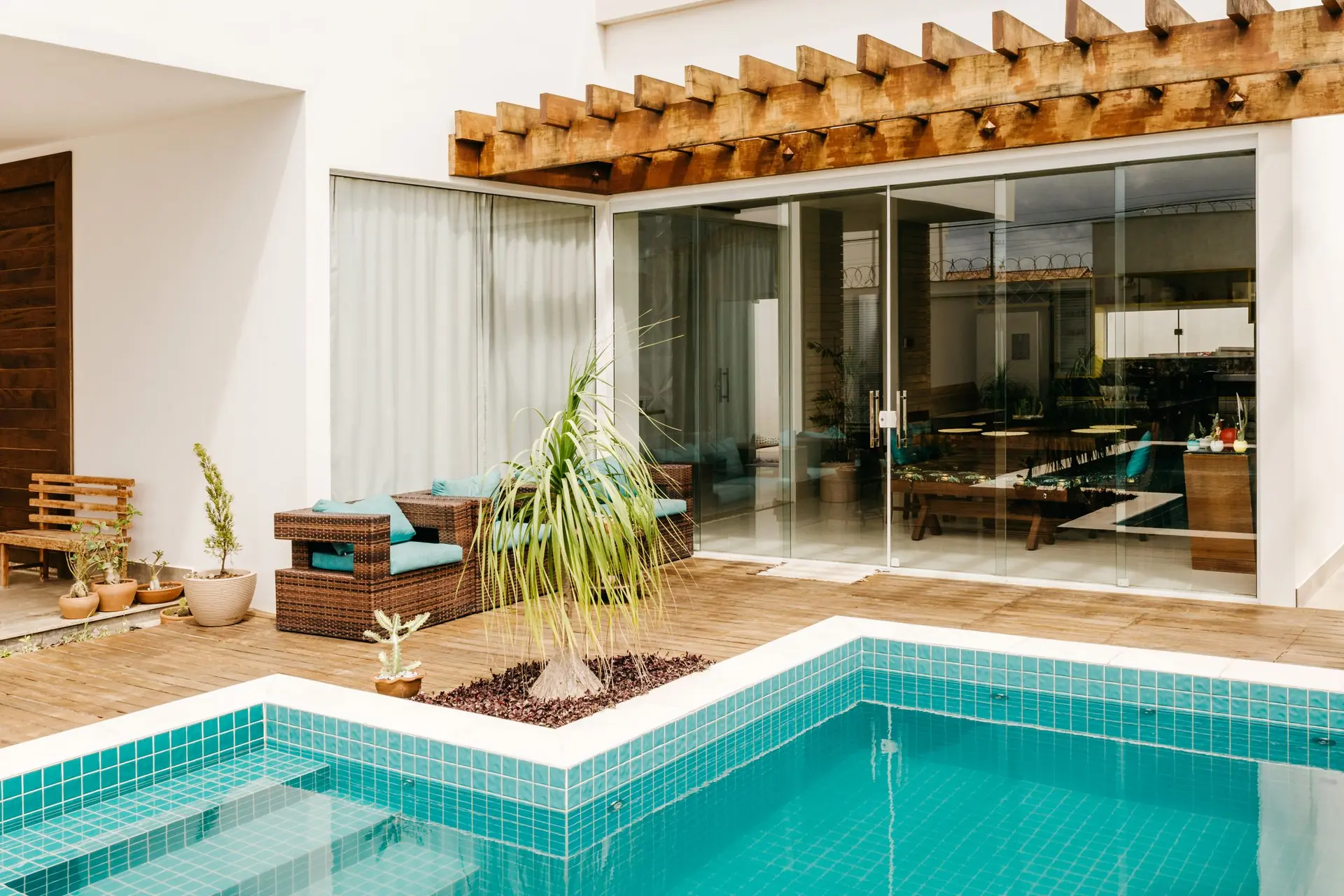 Glass sliding walls and a wood pergola opening onto a pool deck